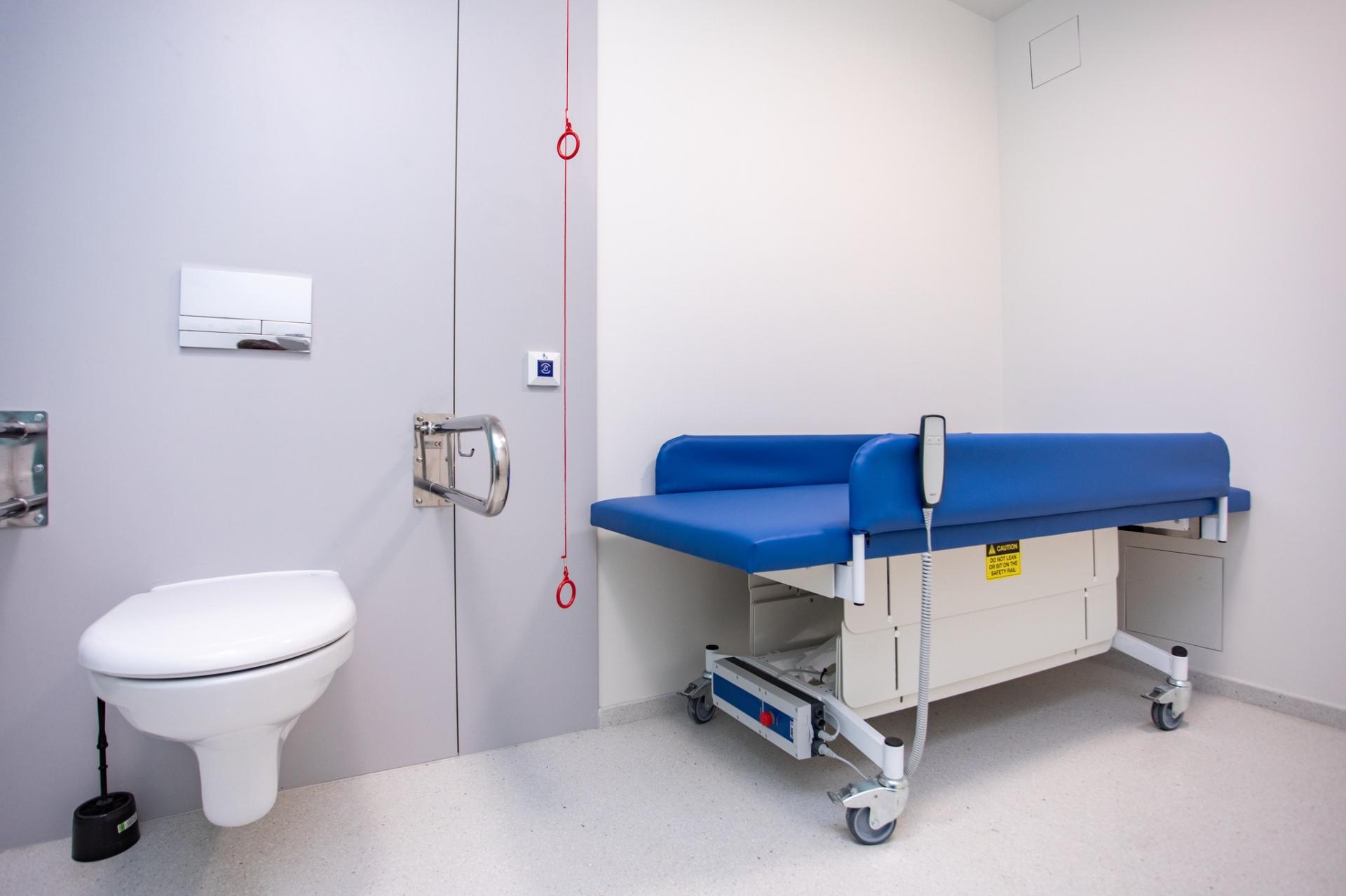 Zdjęcie przedstawia część wyposażenia poznańskiej komfortki: regulowaną mobilną leżankę oraz sedes.